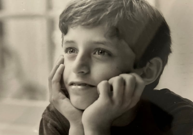 A black and white photo of a boy with his head in his hands