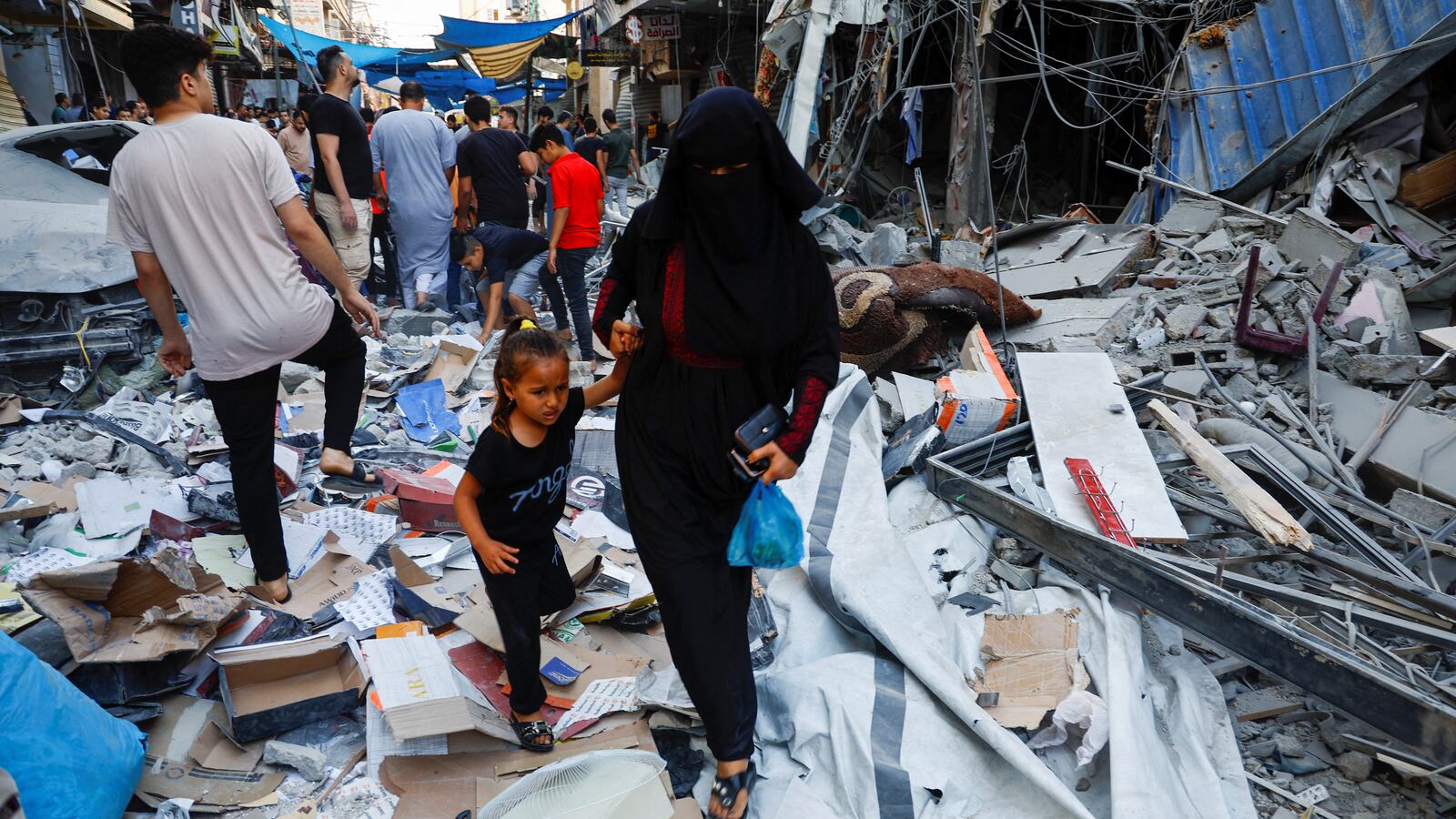 Palestinians walk amidst the rubbles at the site of an Israeli strike in Gaza.