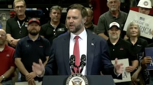 Vice President JD Vance speaking at a manufacturing plant in Missouri standing in front of around a dozen men holding placards that read: "Made in America"