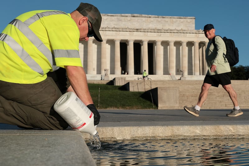 A U.S. National Park Service worker dumps bottles of hydrogen peroxide in the Lincoln Memorial Reflecting Pool as part of their effort to mitigate an algae bloom which followed the completion of recent renovations in Washington, D.C., U.S., June 16, 2026.