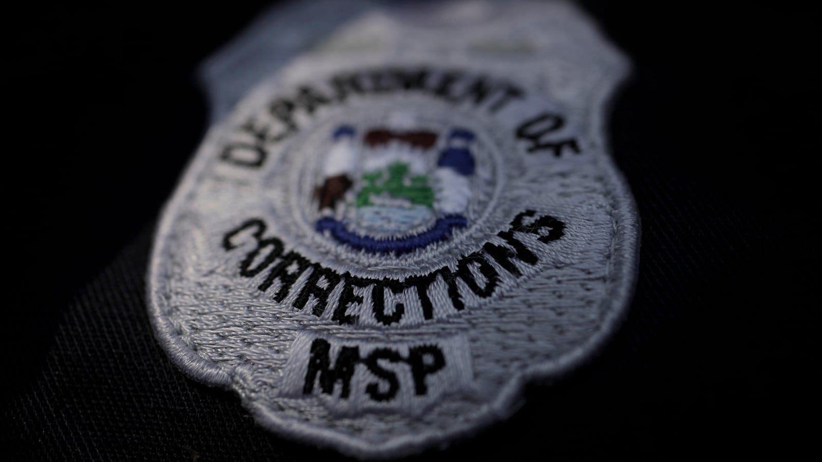 A Maine state prison guard uniform showing the seal of the Dept. of Corrections.
