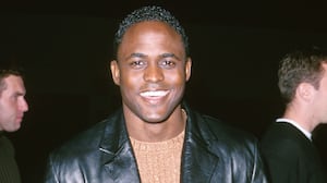 Wayne Brady wearing a black leather jacket and brown sweater in 2000.