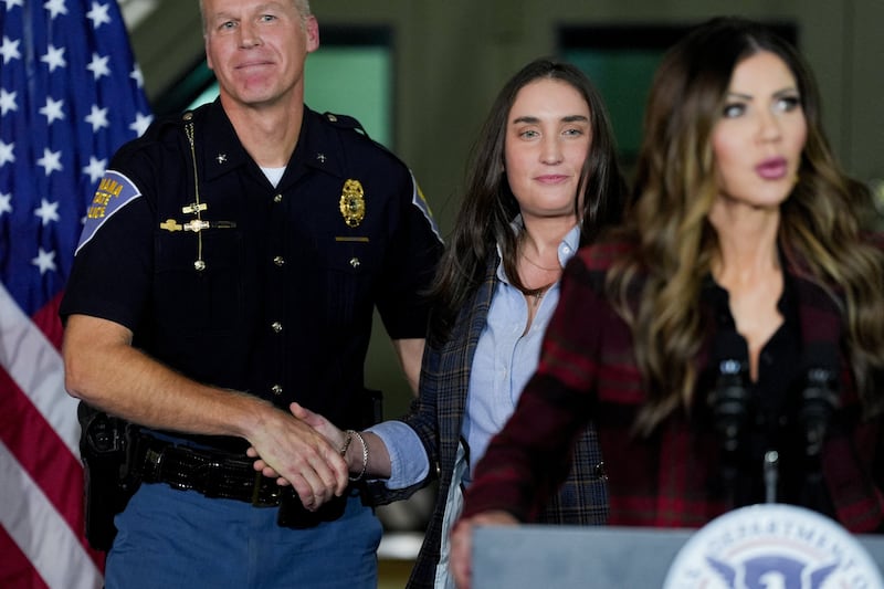 Immigration and Customs Enforcement (ICE) Deputy Director Madison Sheahan shakes hands with Indiana's Secretary of Public Safety Anthony Scott as U.S. Homeland Security Secretary Kristi Noem speaks during a press conference about 'Operation Midway Blitz', an immigration enforcement campaign, from a hangar in Gary, Indiana, U.S., October 30, 2025.