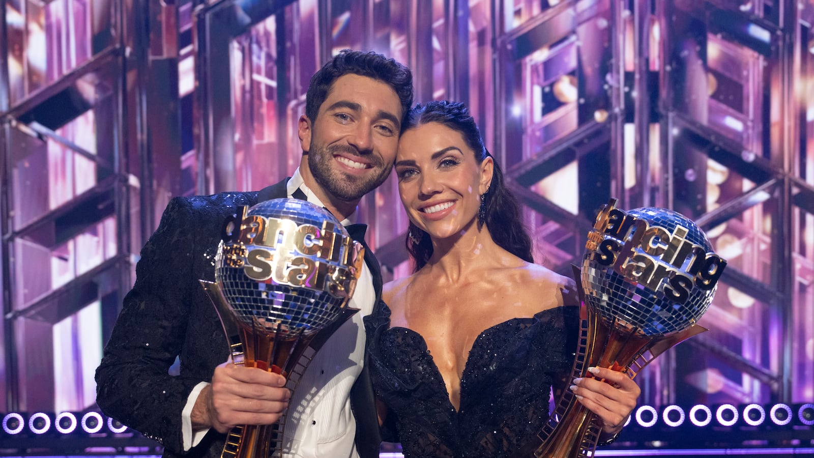 Joey Graziadei and Jenna Johnson pose with their Len Goodman Mirrorball Trophies, awarded for their victory on Dancing With the Stars.