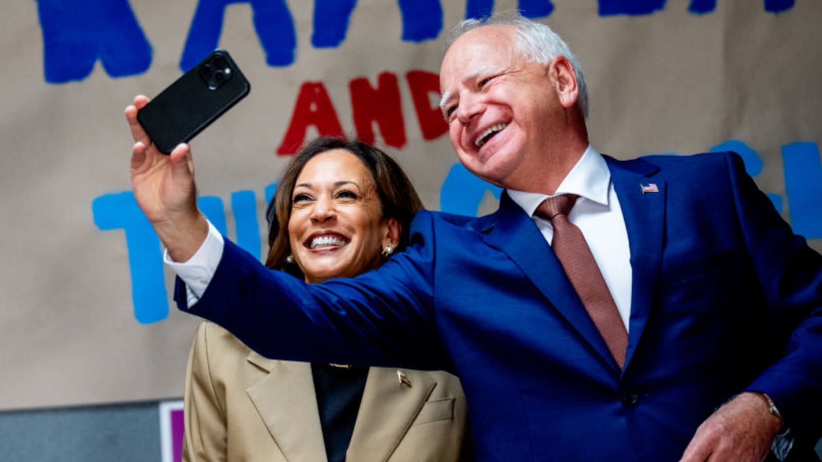 Tim Walz and Kamala Harris pose together for a selfie at a campaign office.