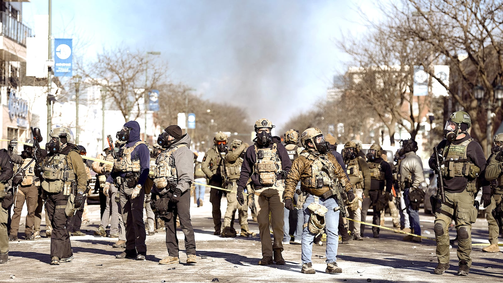 Federal agents face protesters as a dumpster fire burns.