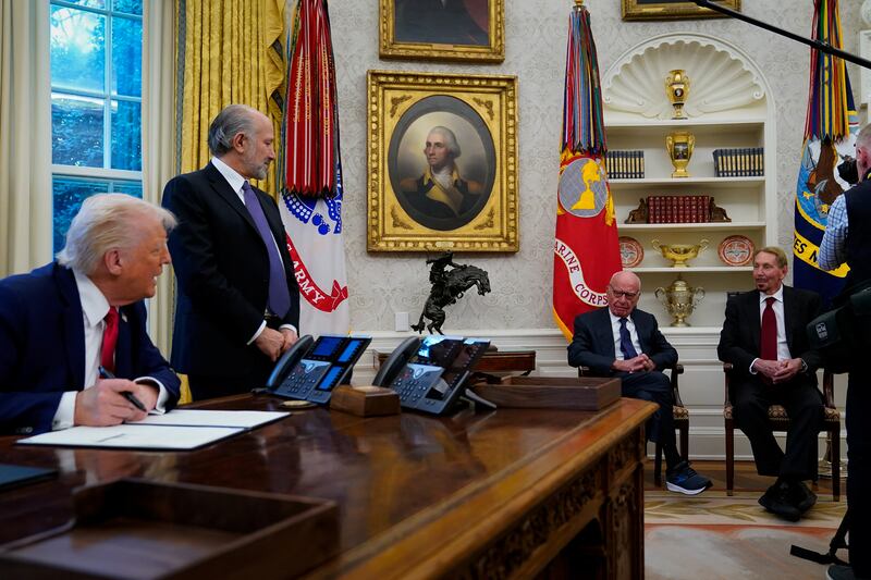 Rupert Murdoch and Larry Ellison look on as U.S. President Donald Trump signs documents in the Oval Office at the White House in Washington on February 3.