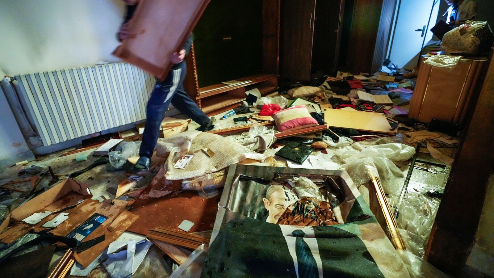 A man walks by a broken portrait of the late Syrian President Hafez Assad as people search for belongings in the ransacked private residence of Syrian President Bashar Assad in the Malkeh district of Damascus, Syria, on Sunday, Dec. 8, 2024. (AP Photo/Hussein Malla)