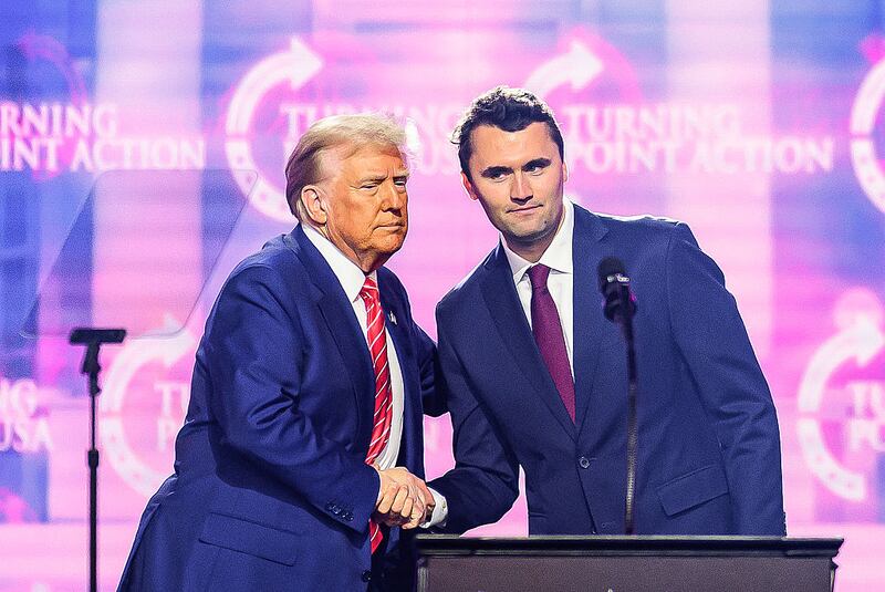 This photo taken on December 22, 2024 shows right-wing activist Charlie Kirk (R) shaking hands with US President Donald Trump as he speaks on stage at America Fest 2024 in Phoenix, Arizona. Right-wing youth activist and influencer Charlie Kirk, a major ally of President Donald Trump, was shot dead on September 10, 2025 in a murder that sparked fears of more political violence in an increasingly febrile United States. Trump confirmed on social media that Kirk, 31, had died from his injuries. (Photo by JOSH EDELSON / AFP) (Photo by JOSH EDELSON/AFP via Getty Images)