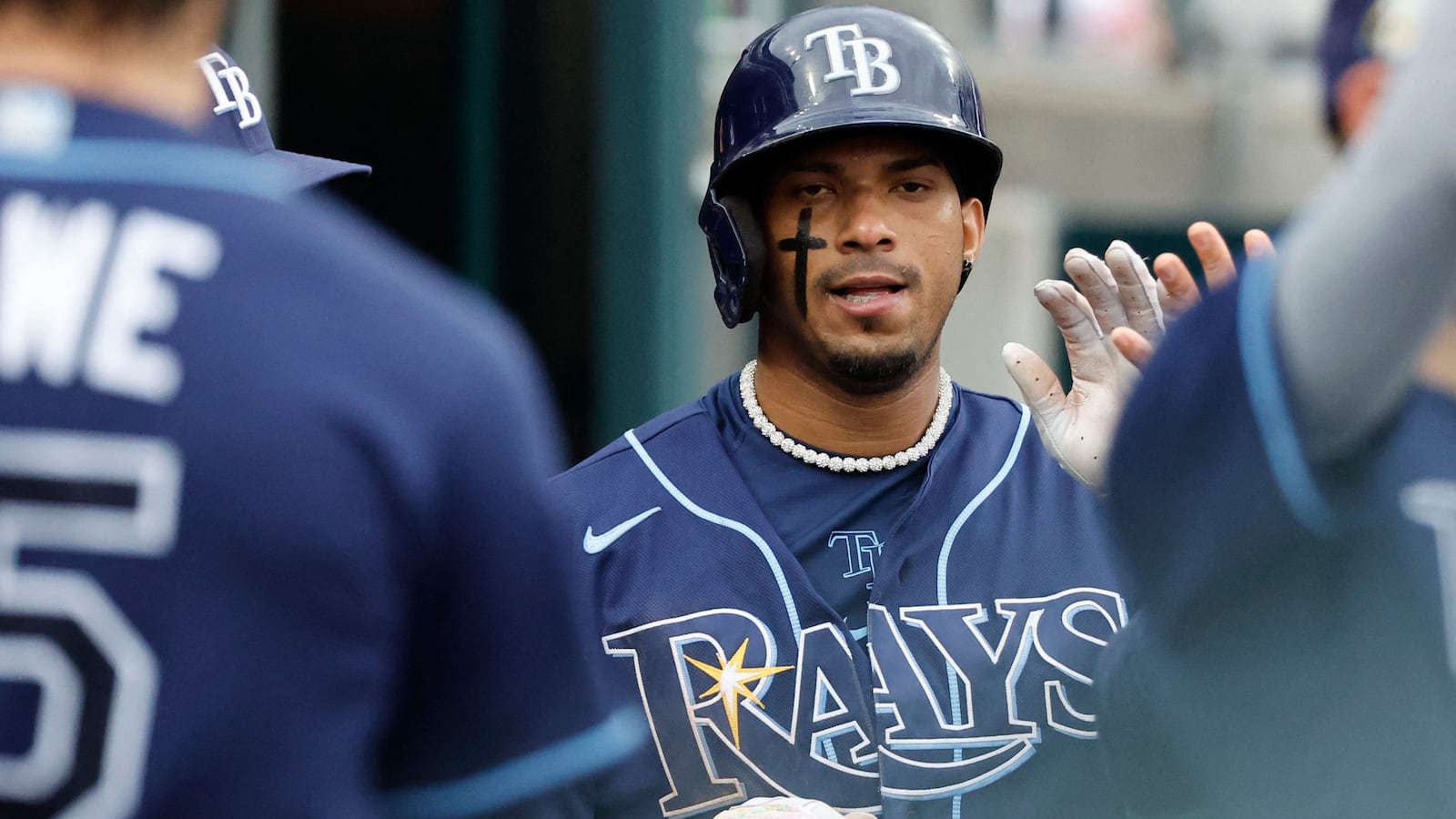 Wander Franco, still wearing a batting helmet, high-fives teammates in a dugout.