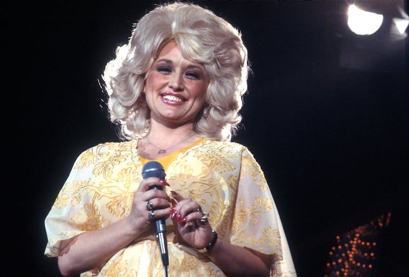 Dolly Parton performs onstage wearing a yellow dress, circa 1975, Los Angeles, California.