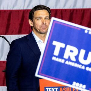 Republican U.S. presidential candidate and Florida Governor Ron DeSantis looks into the crowd after speaking as supporters of former President Donald Trump hold up signs.