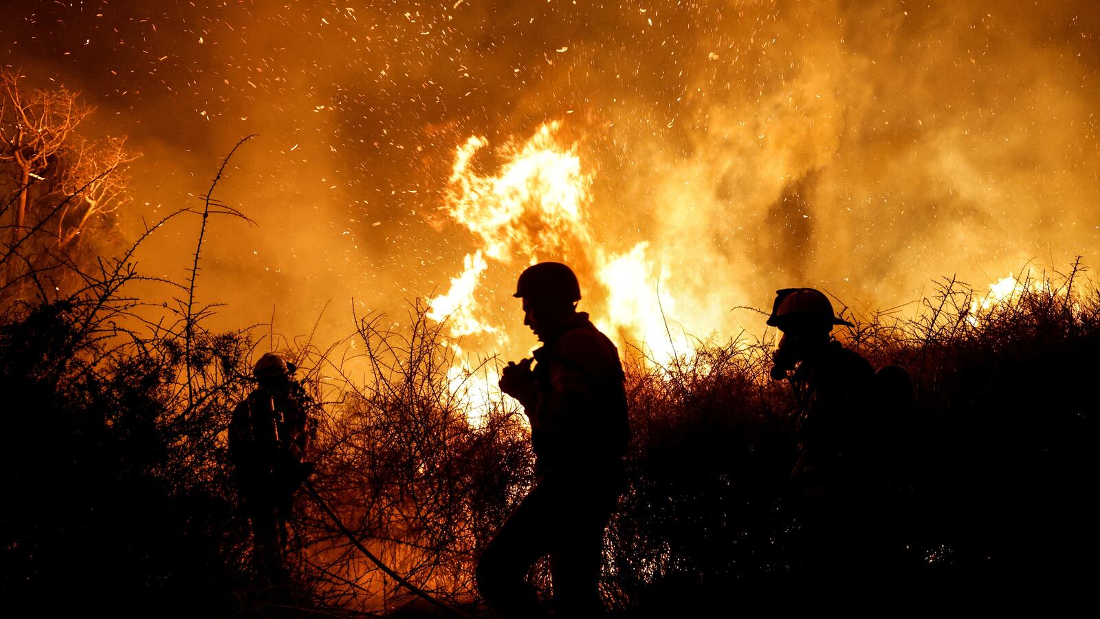Firefighters work to put out a fire in an open field, following a mass-infiltration by Hamas gunmen from the Gaza Strip
