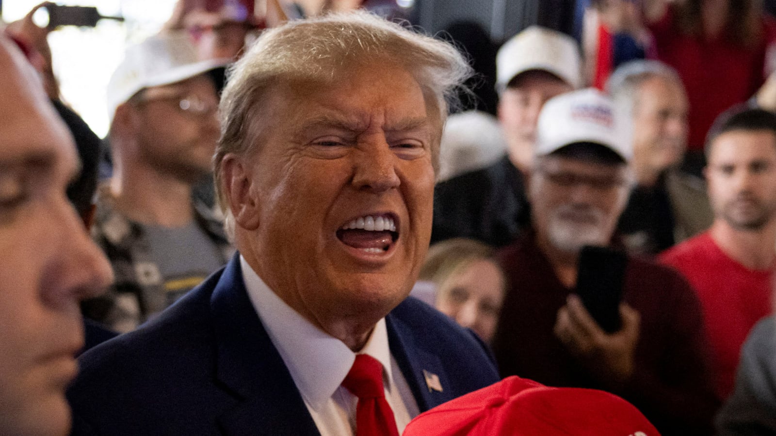 Donald Trump passes a signed hat as he rallies with supporters at a bar in Ankeny, Iowa, Dec. 2, 2023.