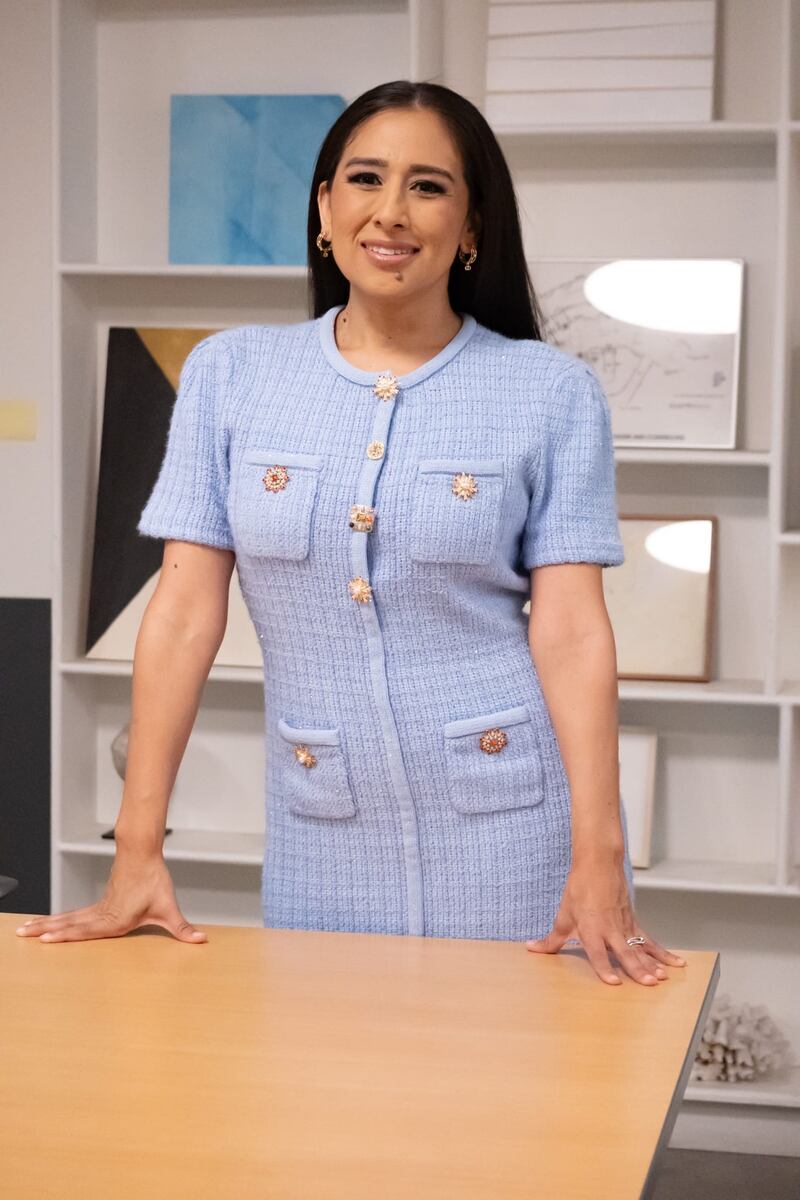 A woman with her hands on a table against a background of books