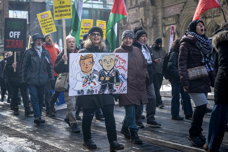 A demonstrator marches carrying a sign depicting US President Donald Trump and Israeli Prime Minister Benjamin Netanyahu with the words "bloody wedding" during protest against the United States and Israel for initiating the Middle East war in Montreal, Quebec, Canada, on March 21, 2026. Washington launched strikes with Israel on Iran on February 28, sparking retaliatory strikes by Tehran against Israel and US bases across the Gulf region. (Photo by ANDREJ IVANOV / AFP via Getty Images)