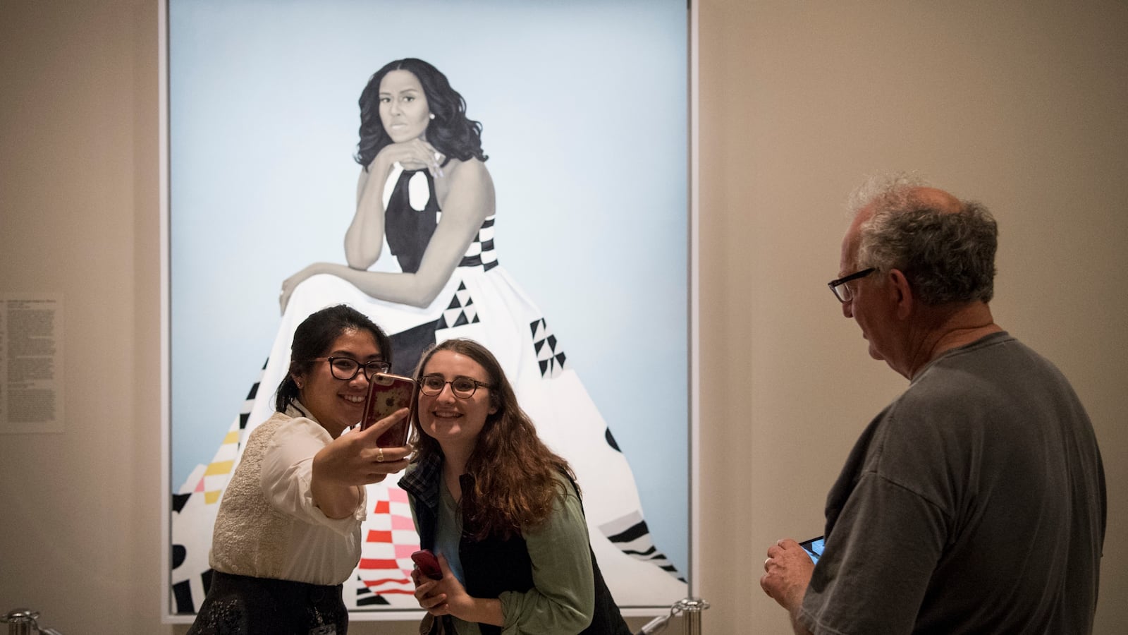 Girls taking a selfie in front of Sherald's portrait of Michelle Obama.