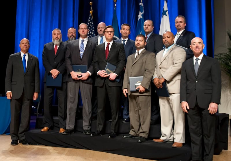 Prior to his arrest for domestic abuse, Samuel L. Saxon was awarded the Secretary’s Meritorious Service Medal in 2016 for his service to the Department of Homeland Security. He can be seen here in the front row wearing a red tie and glasses.