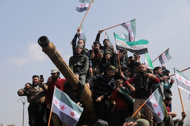 People stand on a Turkish military vehicle during a protest against an agreement on joint Russian and Turkish patrols, at M4 highway in Idlib province, Syria, March 15, 2020. REUTERS/Khalil Ashawi