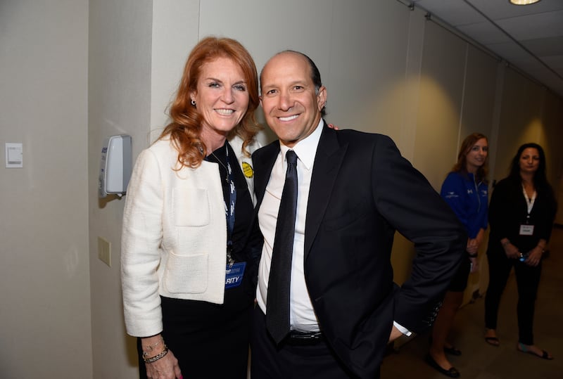 Sarah Ferguson and Howard Lutnick stand in a hallway and pose for a photos