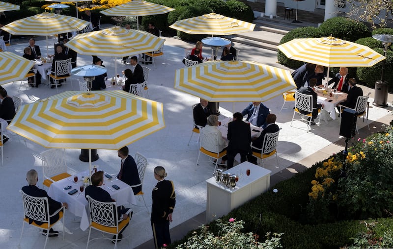 President Donald Trump (far right) sits down after speaking at a luncheon in the concrete covered Rose Garden of the White House in Washington, D.C. on October 21, 2025.
