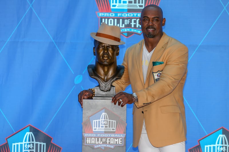Brian Dawkins places his hat on his bust as he poses for photographers next to his Hall of Fame bust after he was enshrined into the Pro Football Hall of Fame during the 2018 Pro Football Hall of Fame Enshrinement Ceremony on August 4, 2018, at the Tom Benson Hall of Fame Stadium, Canton, Ohio.