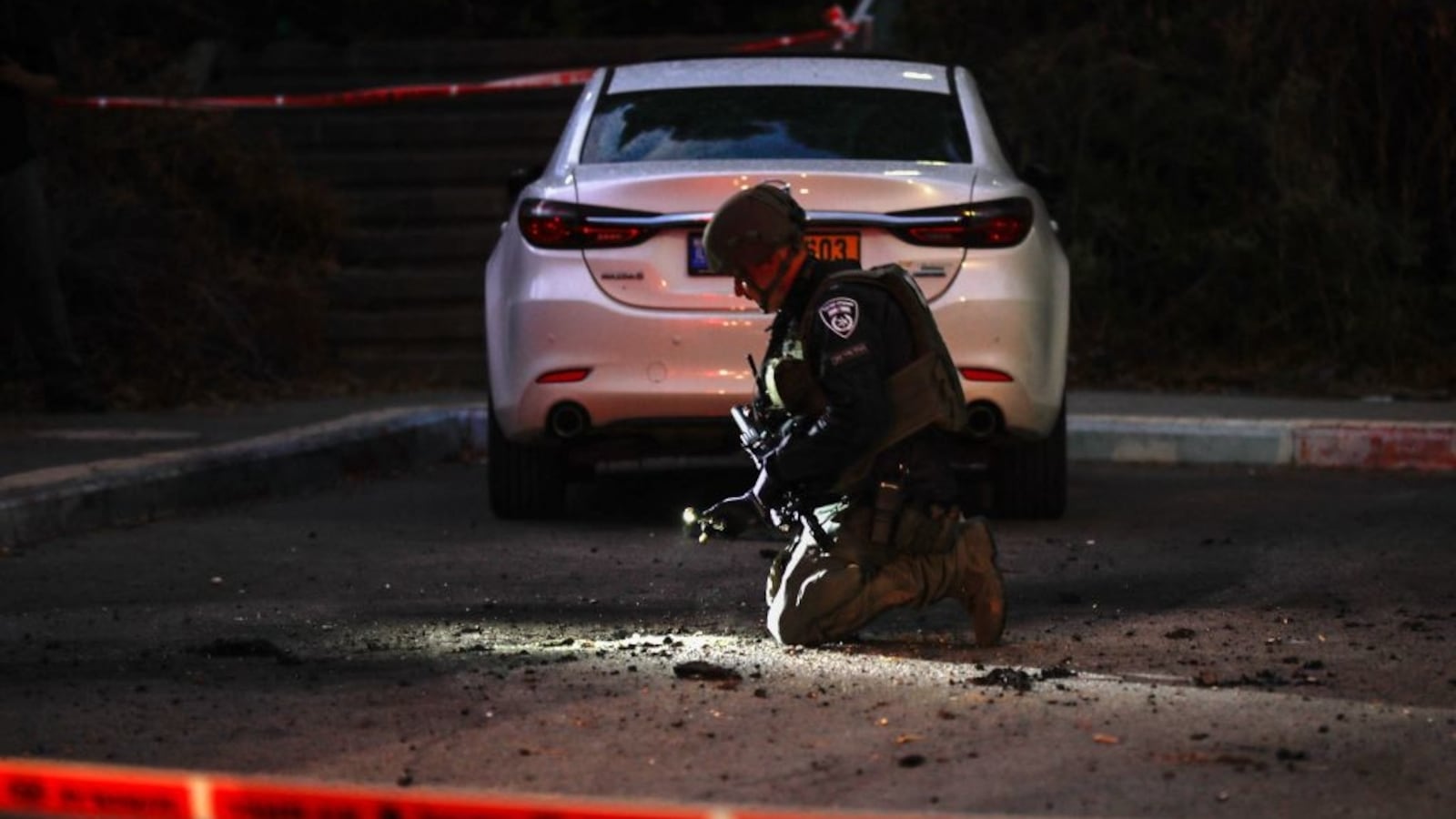 A member of Israeli security forces inspects a site where a rocket launched from Lebanon fell in the northern city of Kiryat Shmona near the border on Oct. 19, 2023.
