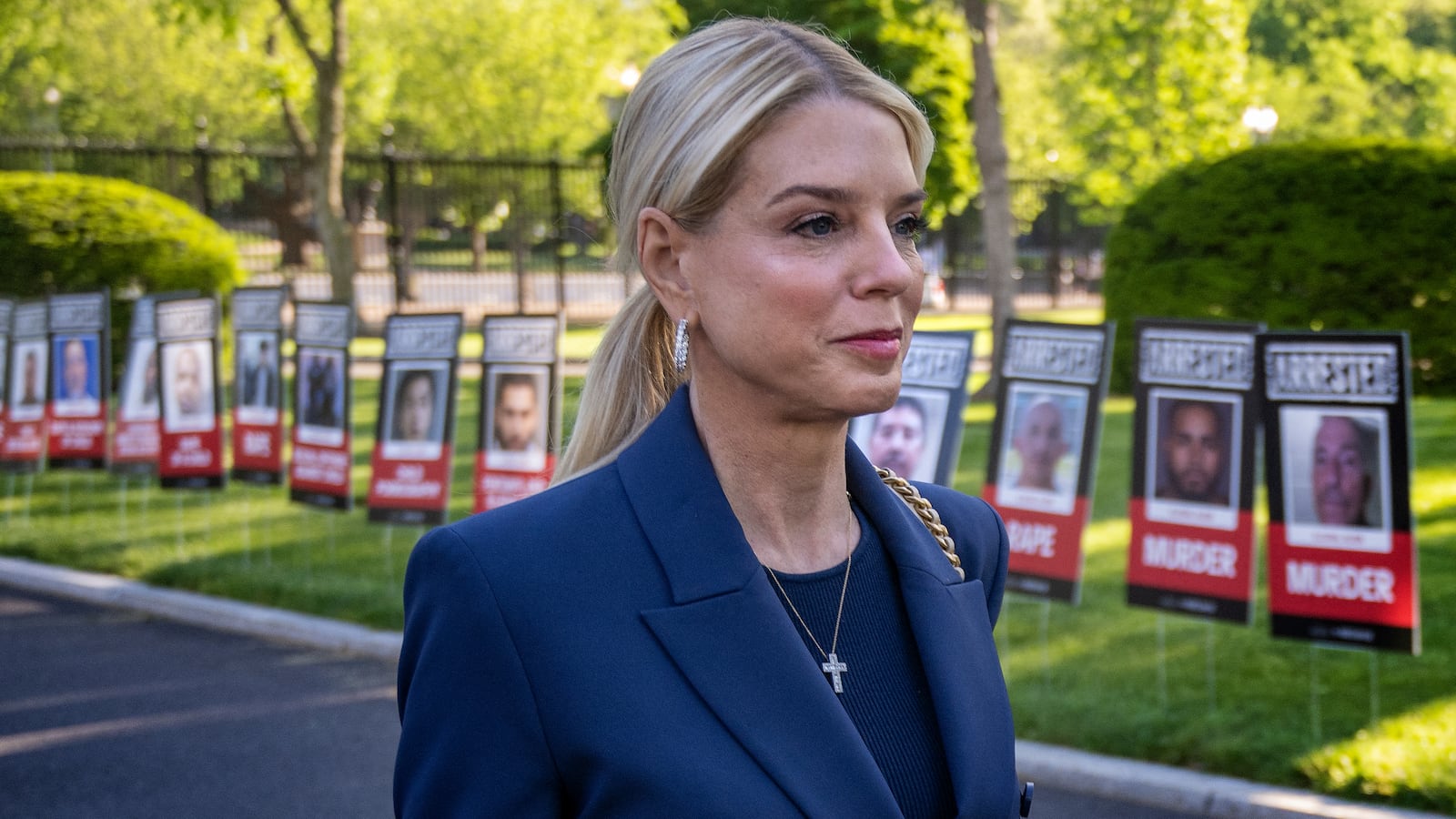 US Attorney General Pam Bondi walks past placards with the mugshots of undocumented immigrants.