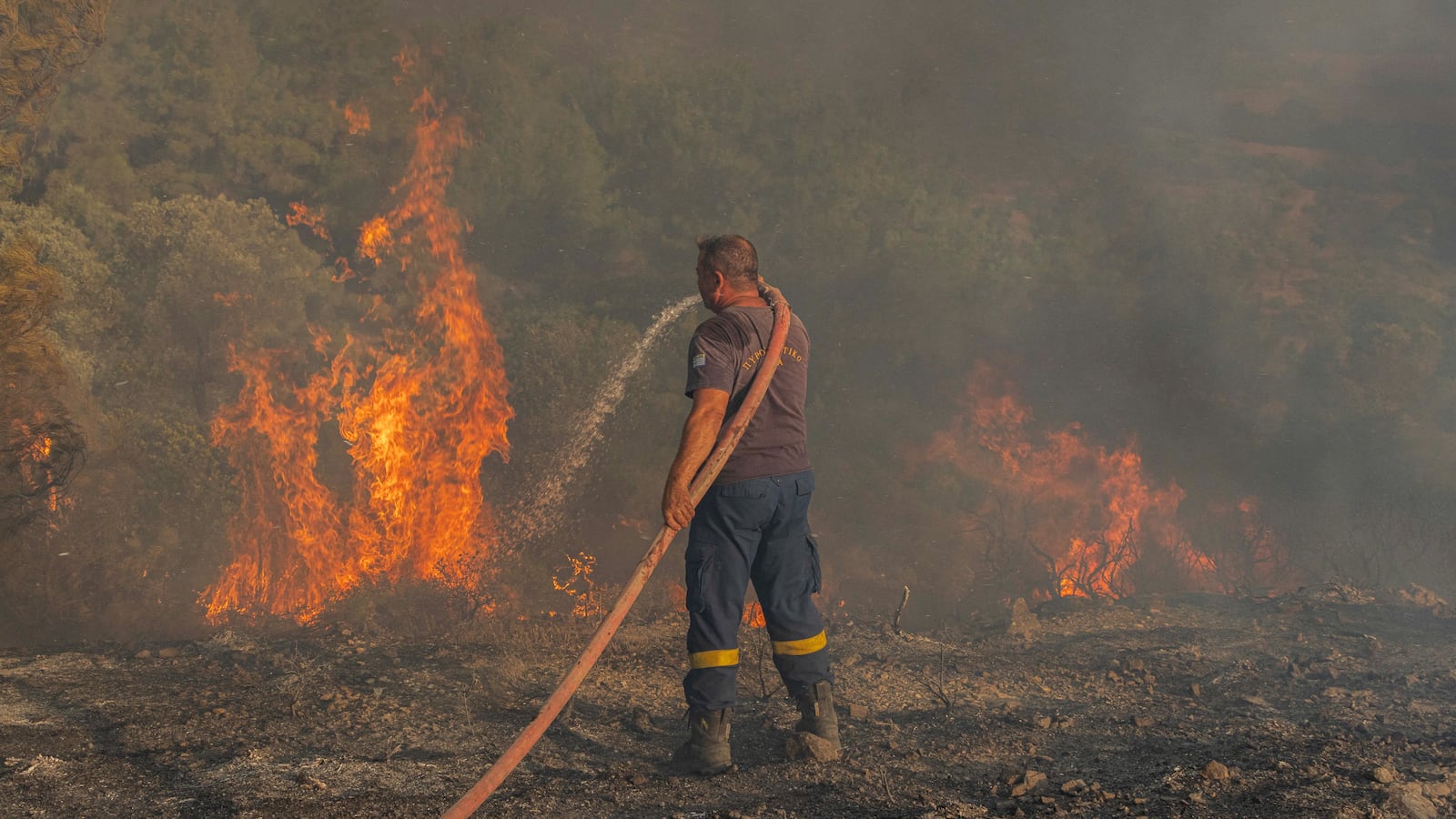 Firefighter Nektarios Kefalas tries to extinguish a wildfire burning near the village of Asklipieio, on the island of Rhodes, Greece, July 24, 2023.