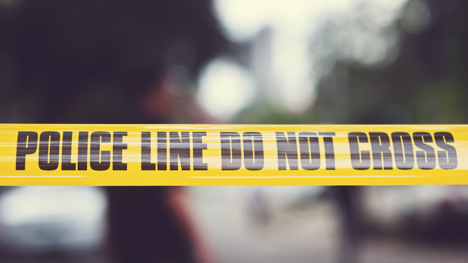 Yellow police tape that reads “do not cross” with a blurred background.