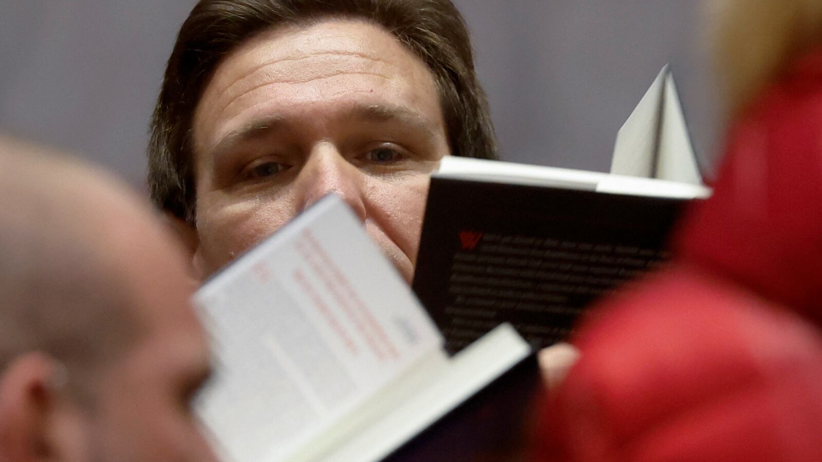Ron DeSantis peers over books
