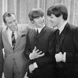 Ed Sullivan with his arms around the members of The BEatles