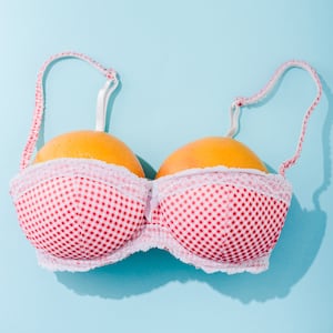 top view of a polka-dot bra with two oranges on blue (breasts concept)