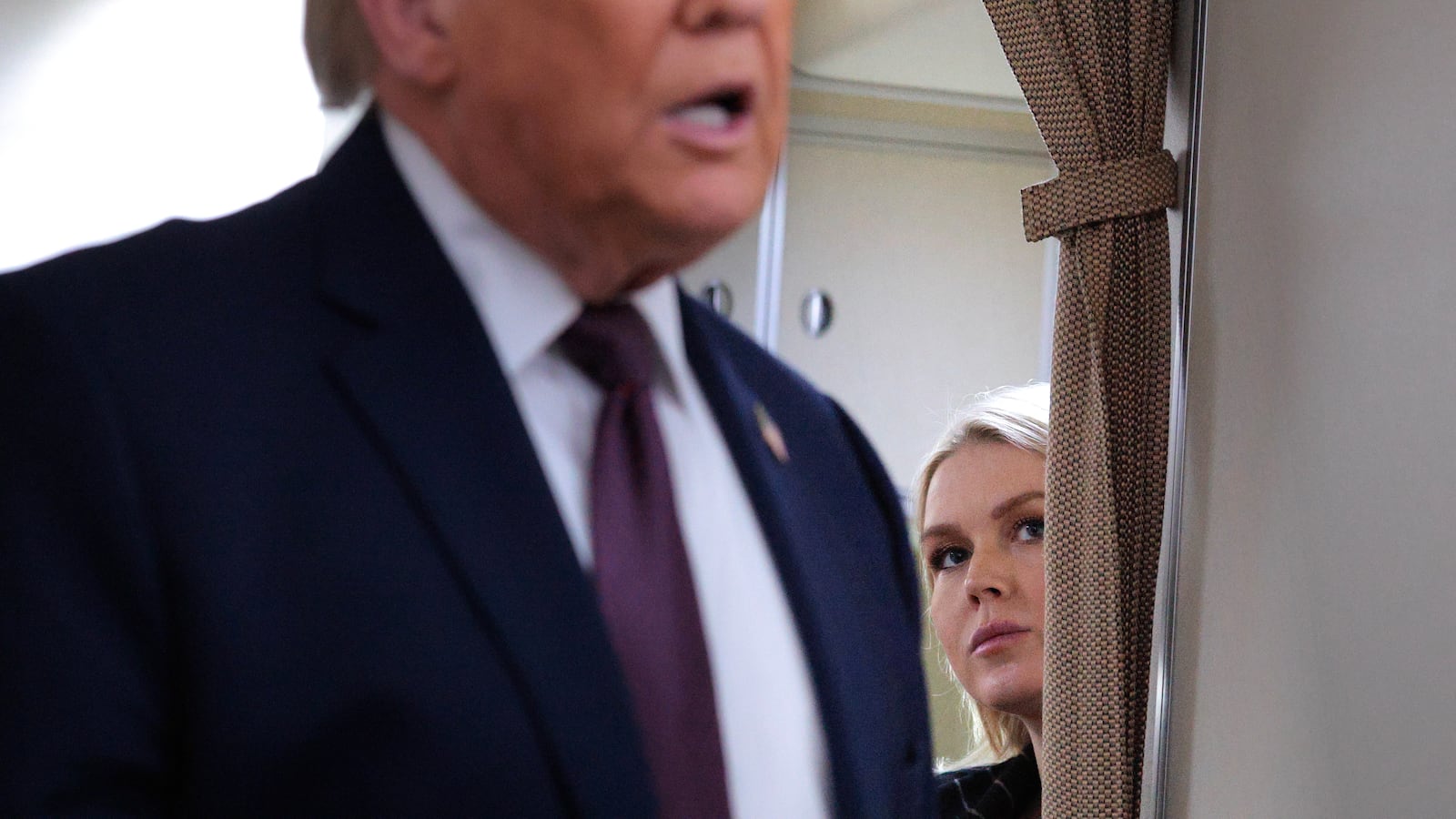 White House Press Secretary Karoline Leavitt listens to U.S. President Donald Trump speak to reporters on board Air Force One