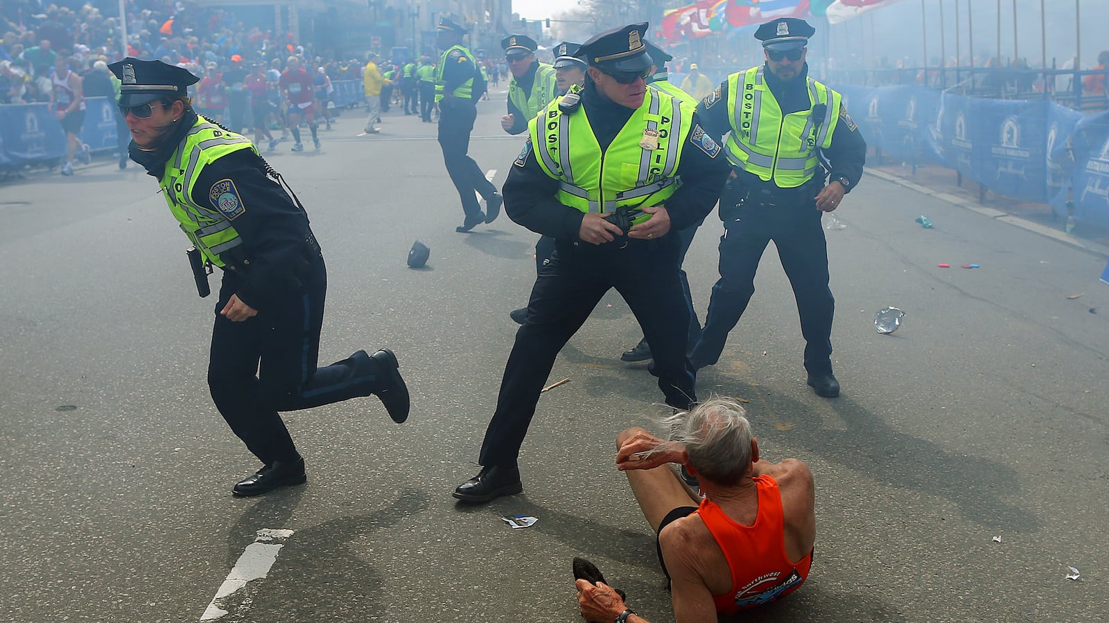 Police officers with their guns drawn hear the second explosion down the street. The first explosion knocked down 78-year-old US marathon runner Bill Iffrig at the finish line of the 117th Boston Marathon.
