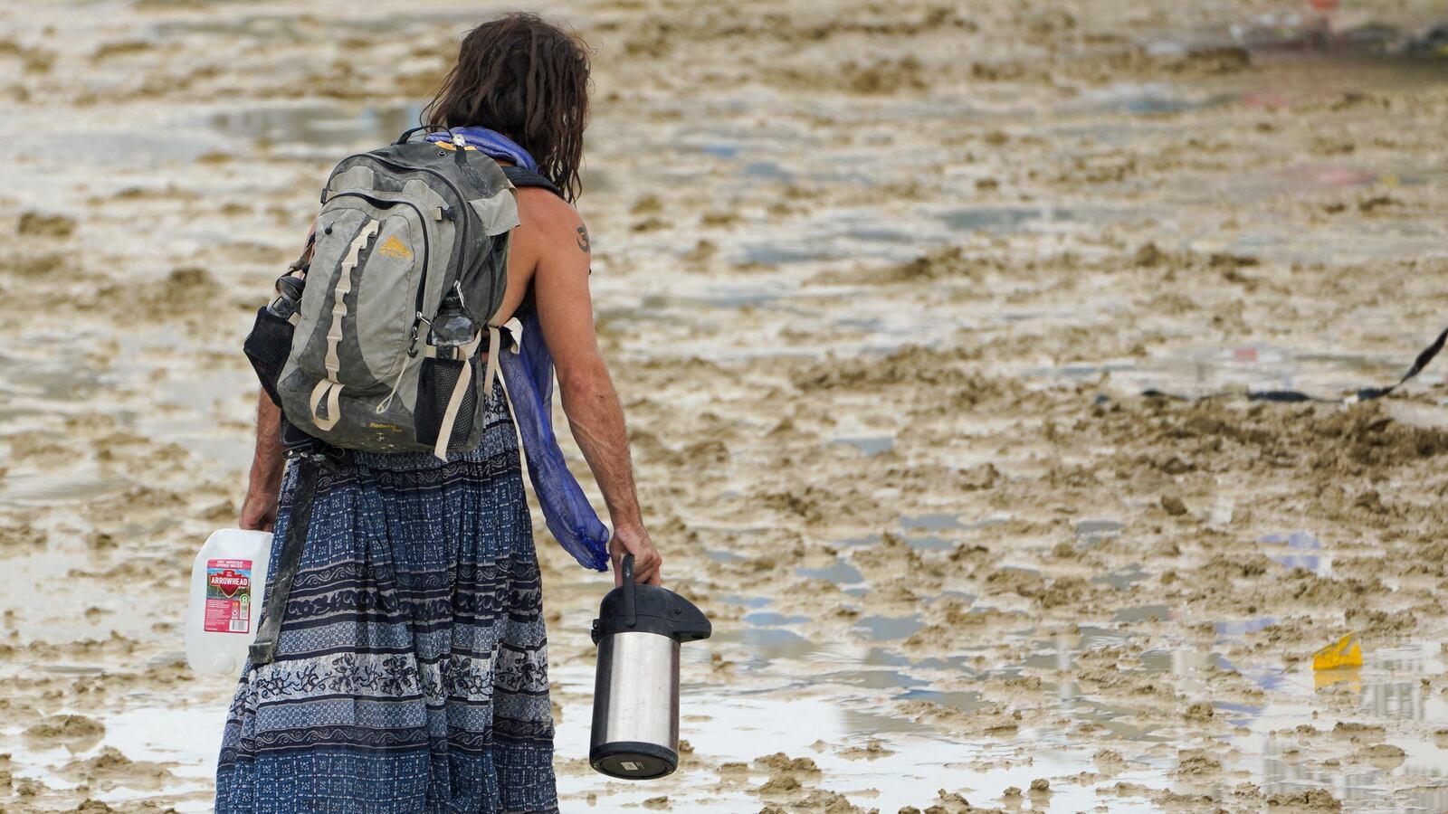 A Burning Man participant makes their way through the mud in Black Rock City, in the Nevada desert, after a rainstorm turned the site into mud September 2, 2023.
