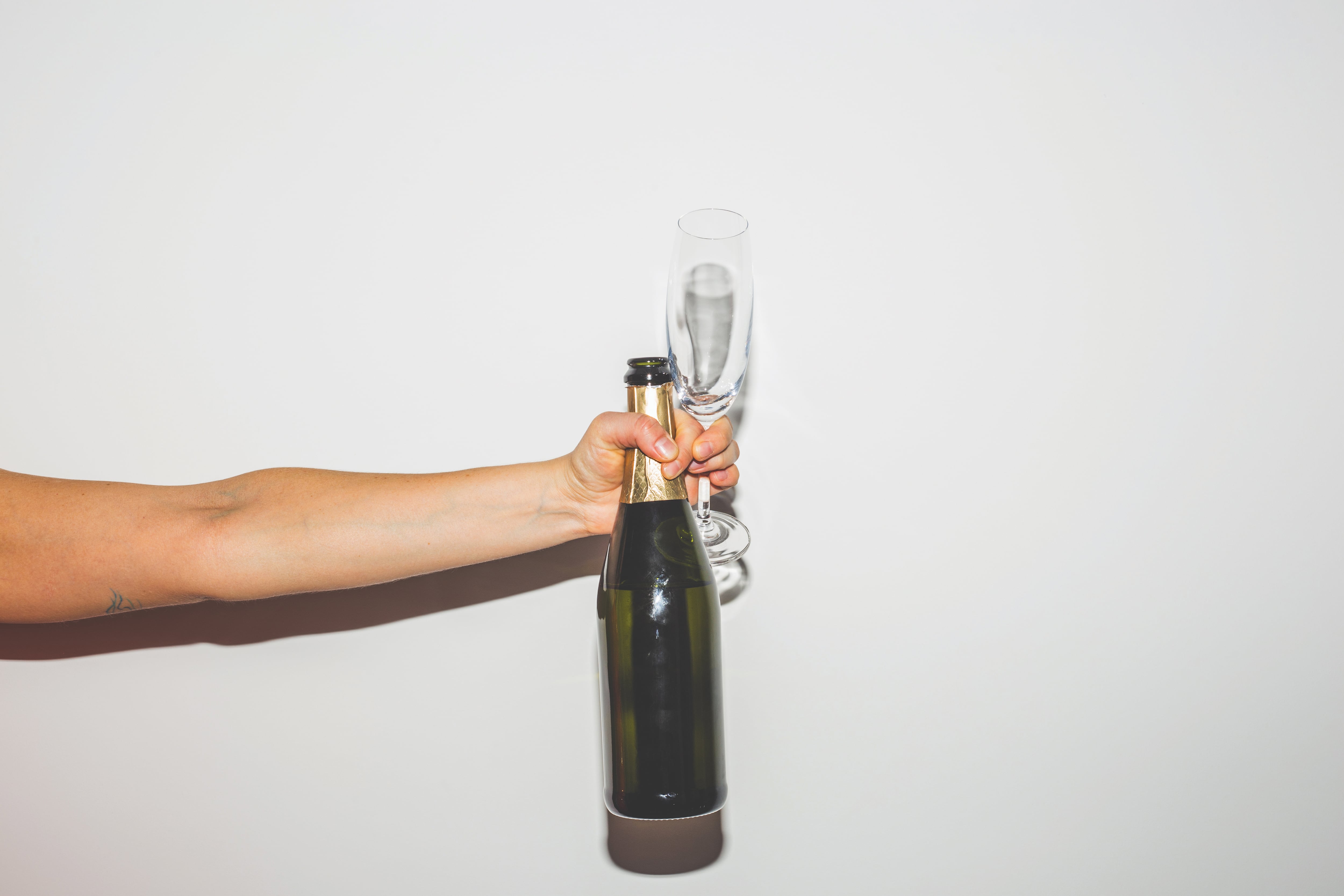 Hand holding a bottle and a glass of Champagne