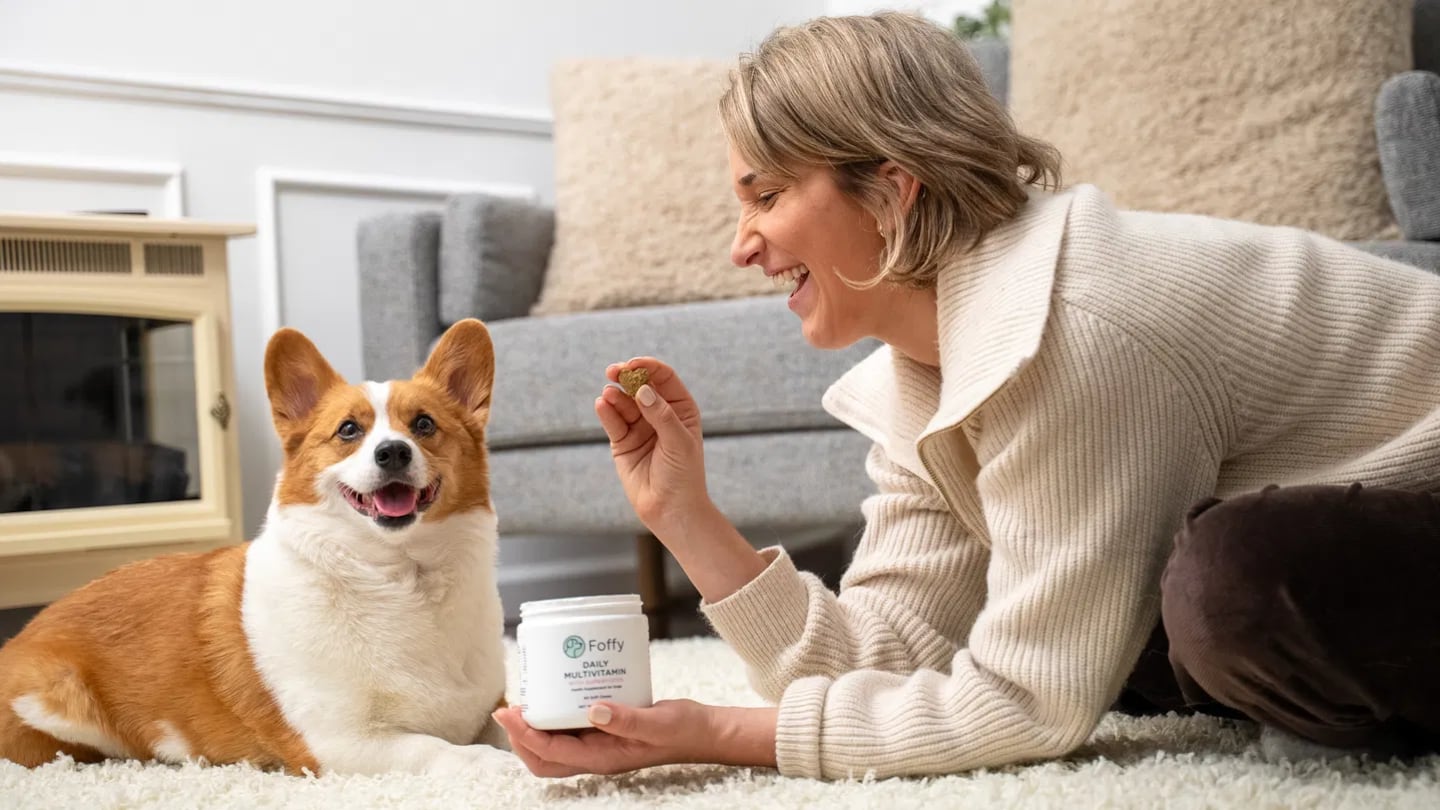 Woman feeding a Foffy daily pet multivitamin chew to her dog