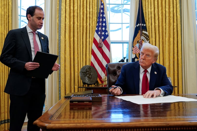 U.S. President Donald Trump signs executive orders as White House Staff Secretary Will Scharf stands by in the Oval Office at the White House in Washington, U.S., January 30, 2025. REUTERS/Elizabeth Frantz