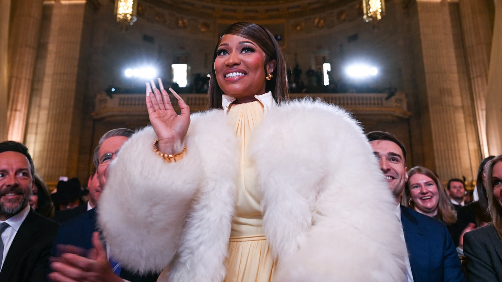 Trinidadian rapper and singer-songwriter Nicki Minaj stands as she is recognized by US President Donald Trump as he delivers remarks on 'Trump Accounts' at the Andrew W. Mellon Auditorium in Washington, DC, on January 28, 2026. (Photo by Brendan SMIALOWSKI / AFP via Getty Images)
