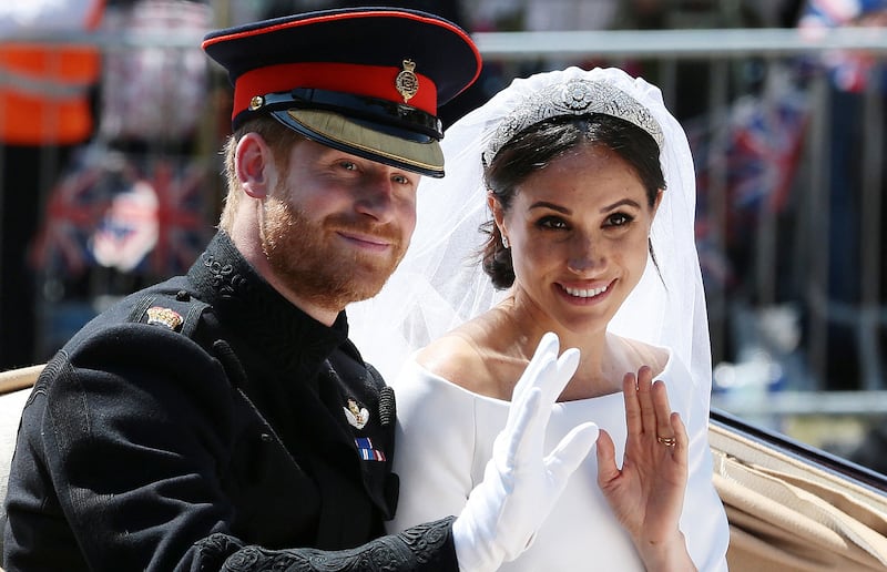 Prince Harry, Duke of Sussex, and his wife Meghan, Duchess of Sussex, wave from a royal carriage as they head back towards Windsor Castle after their wedding ceremony on May 19, 2018.
