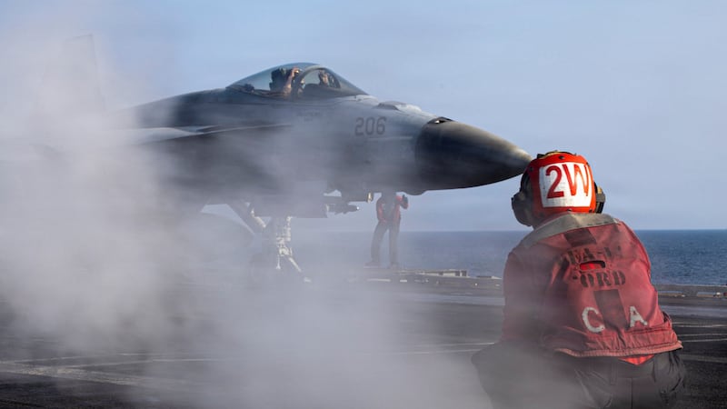 A U.S. Navy sailor prepares to launch an F/A-18E Super Hornet from the flight deck of the USS Abraham Lincoln.