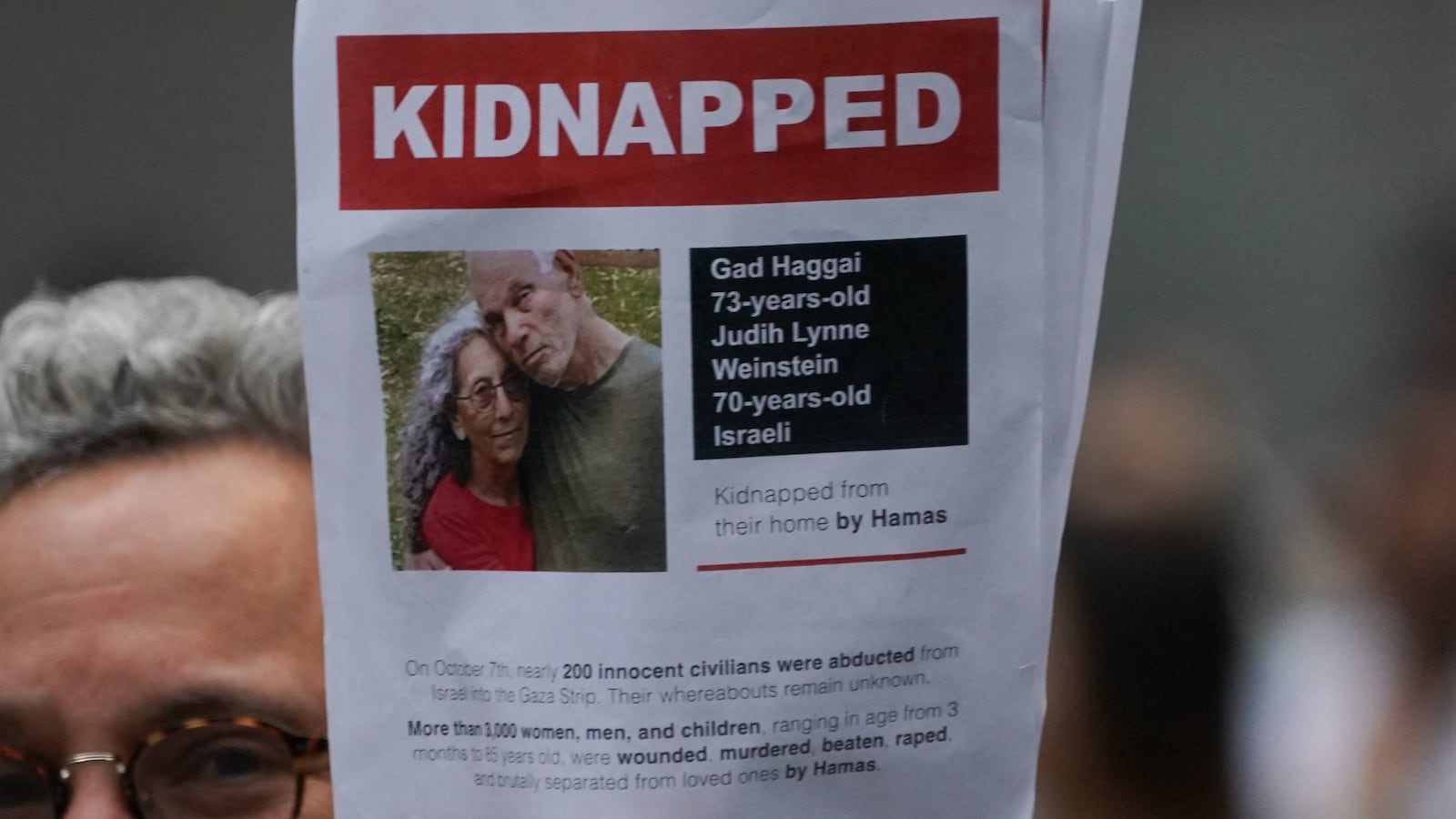 A supporter of Israel holds a picture of kidnapped Israeli hostages Gad Haggai and Judith Lynne Weinstein during the \"Flood Wall Street for Gaza\" rally outside the New York Stock Exchange on October 26, 2023 in New York