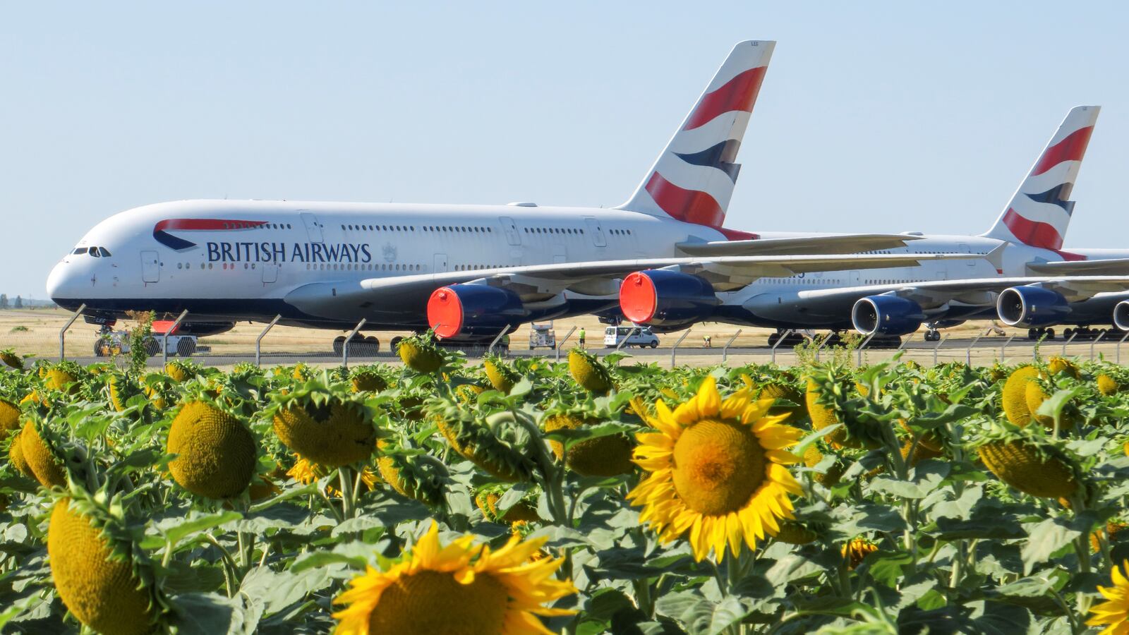 Technicians move a British Airways Airbus A380 airplane stored on the tarmac