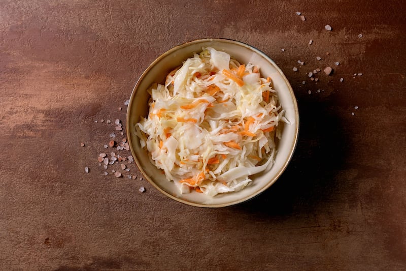 Traditional Sauerkraut Cabbage with Carrots In Ceramic Bowl. Sea Salt Nearby. Healthy Food. Fermented Products. Brown Textured Background. Top View. Copy Space. (Photo by: Natasha Breen/REDA/Universal Images Group via Getty Images)