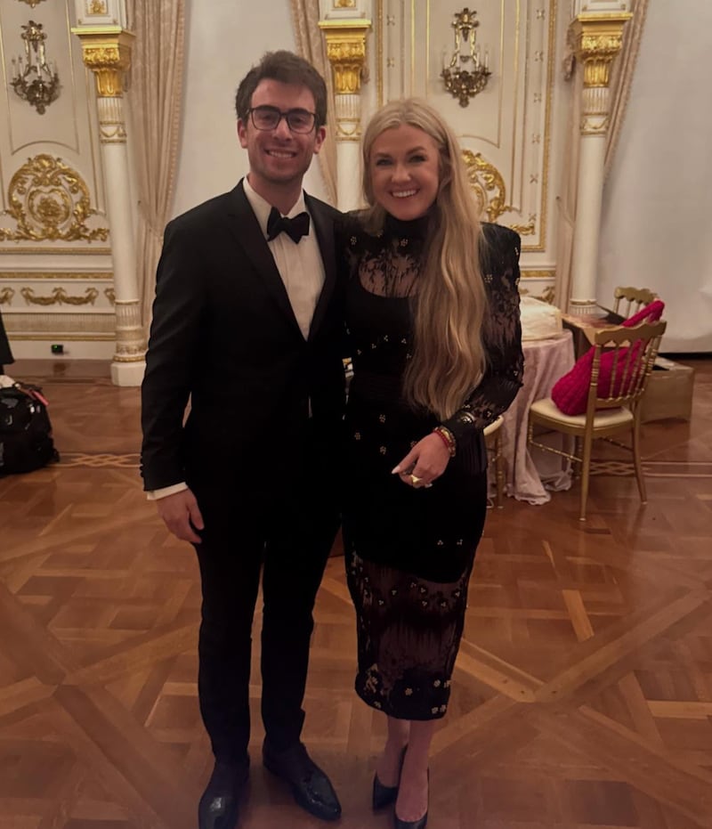 Blake Wynn and Erika Kirk pose for the camera in an ornate ballroom.
