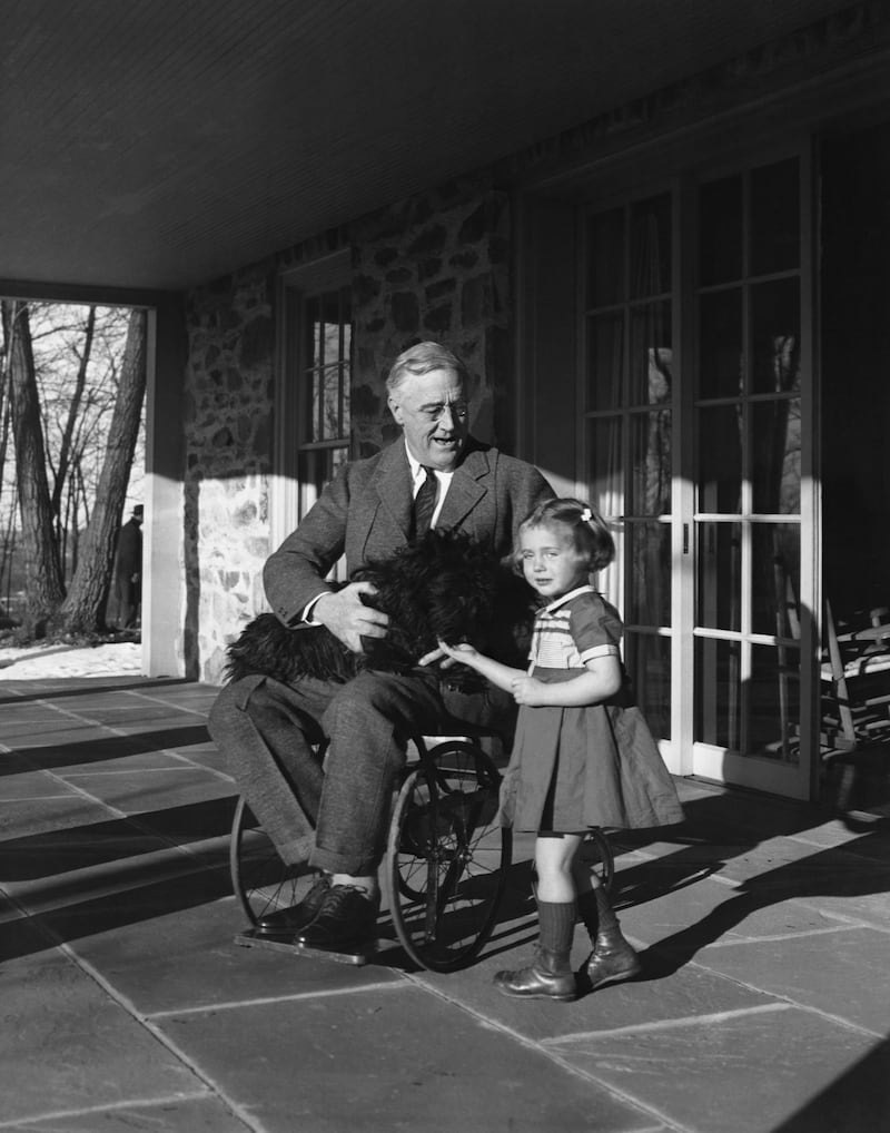 Franklin Roosevelt holds his Scotch terrier, Fala, on his lap as he talks to Ruthie Bie, the daughter of the Hyde Park caretaker.