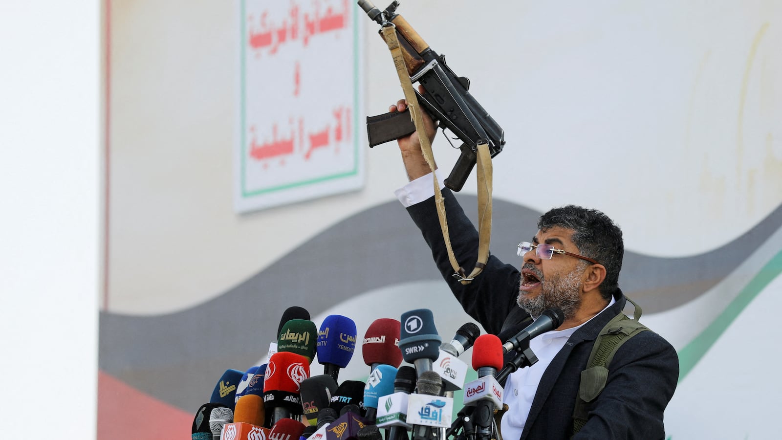 Mohammed Ali al-Houthi, a member of the Houthi supreme political council, speaks while holding a gun, as supporters of the Houthi movement rally to denounce air strikes launched by the U.S. and Britain on Houthi targets, in Sanaa, Yemen