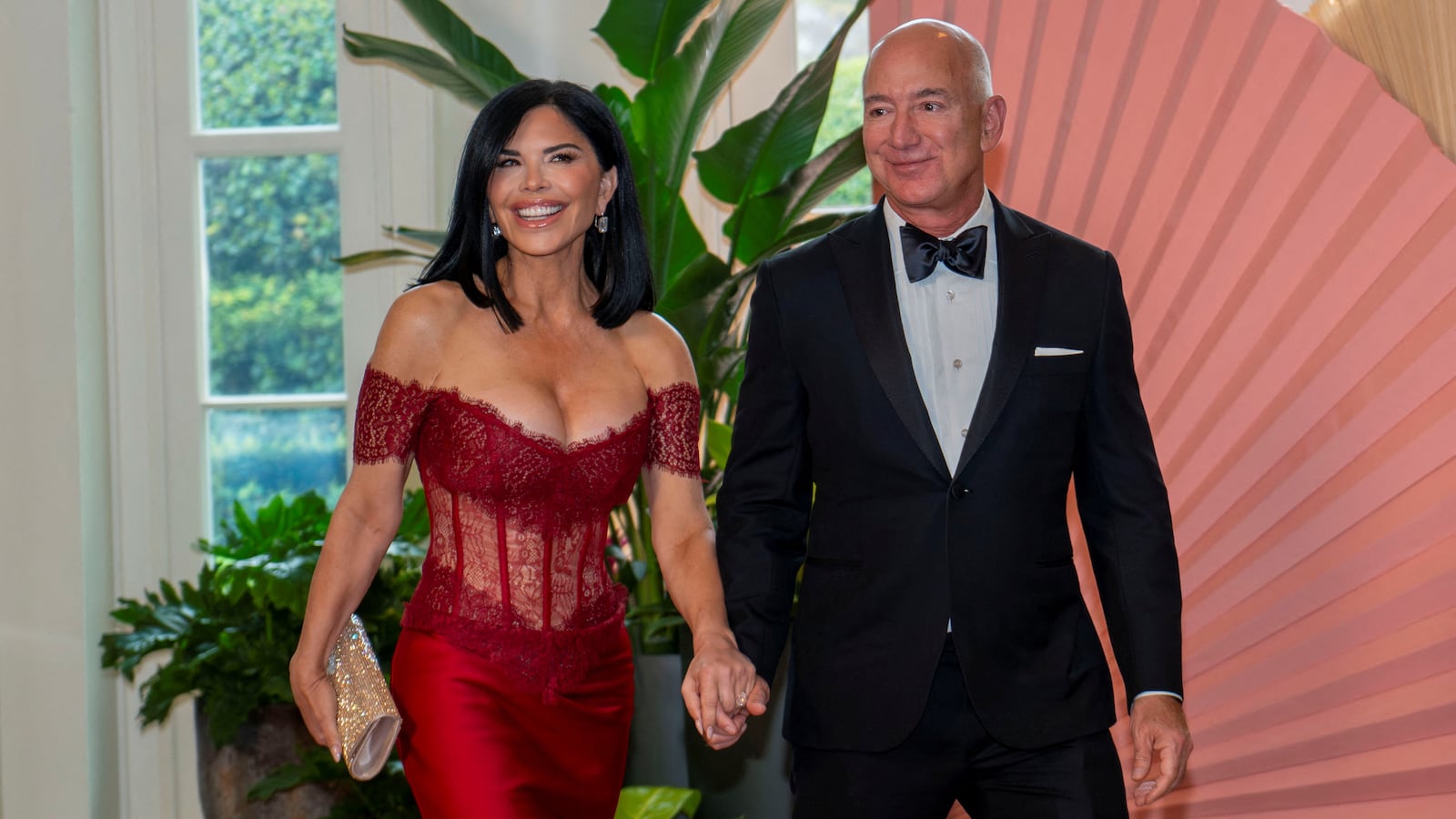 Amazon CEO Jeff Bezos (wearing a tuxedo) and Lauren Sanchez (wearing a scarlet red lace and silk gown) arrive for a State Dinner honoring Japan's Prime Minister at the White House.