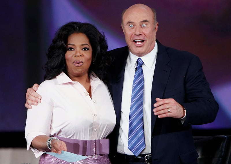 U.S. talk show host Oprah Winfrey smiles as television personality Dr. Phil reacts to seeing himself in a television screen after having his moustache shaved off during a special show at Radio City Music Hall in celebration of O Magazine's 10th anniversary in New York City, May 7, 2010.